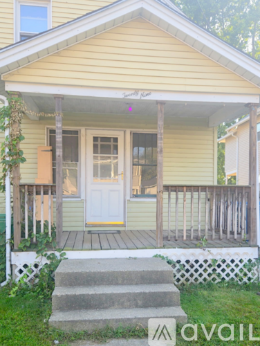 A yellow house with a white door and a porch.