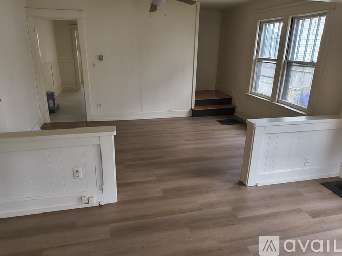 A room with wooden flooring and white walls.