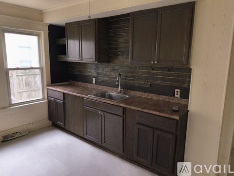 A kitchen with dark brown cabinets and a granite countertop.