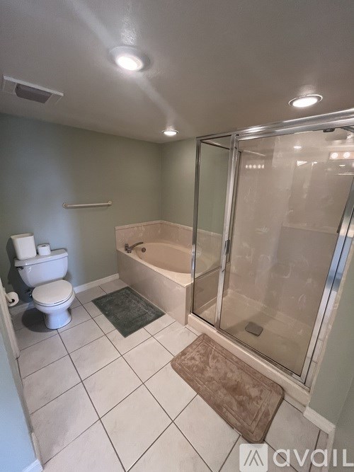 A bathroom with a toilet, bathtub, and glass shower door.