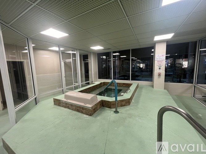 A spacious indoor area with a hot tub and glass walls.