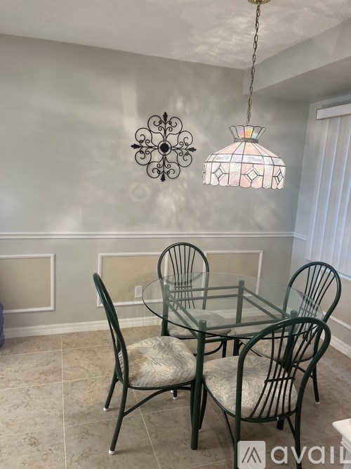 A glass dining table with four chairs and a hanging light fixture.