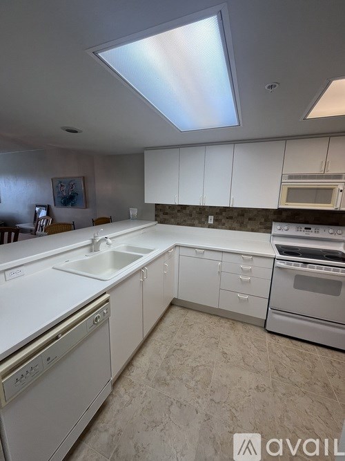 A kitchen with white appliances and a skylight.