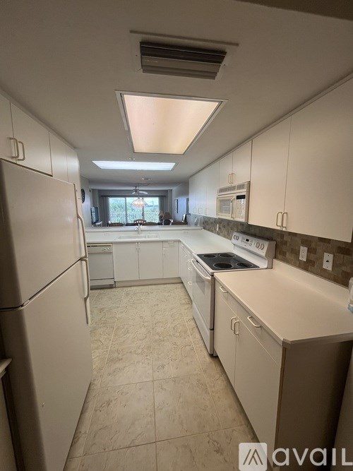 A kitchen with white appliances and cabinets.