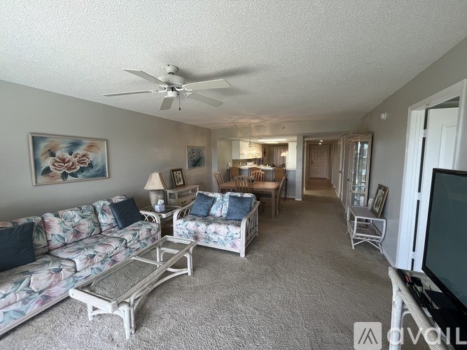 A living room with a floral sofa, a coffee table, and a television.