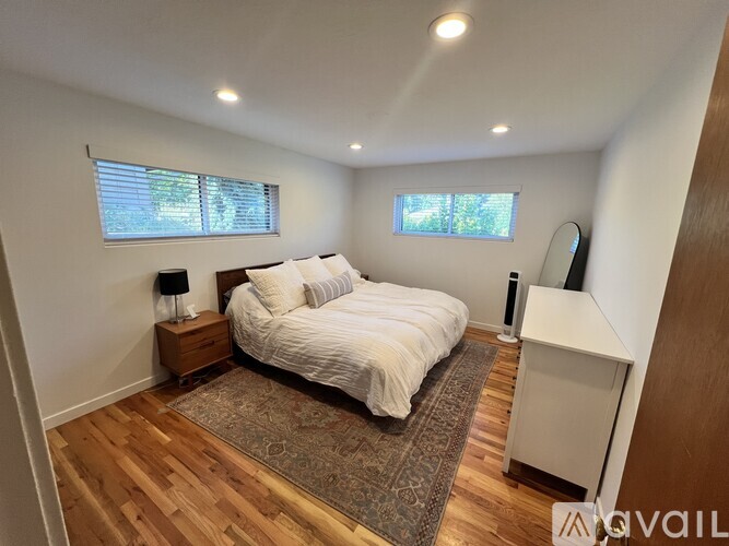 A bedroom with a bed, nightstand, and window.