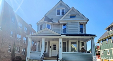 A two-story house with a front porch and a balcony on the second floor.