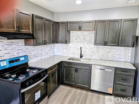 A kitchen with a black stove top oven and a white marble backsplash.