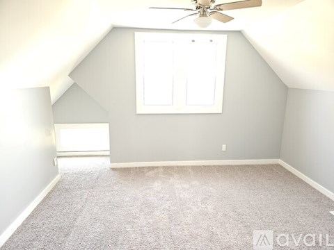 A room with a carpeted floor, a ceiling fan, and a window with blinds.