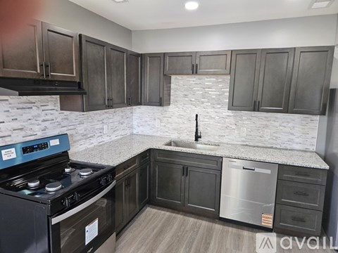 A kitchen with a stove, sink, and cabinets.