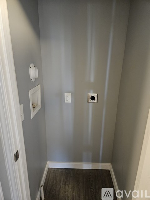 A hallway with a white door and a light switch on the wall.