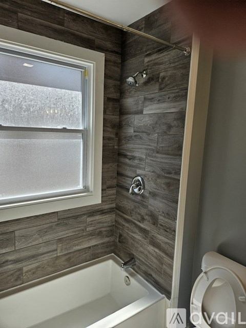 A bathroom with a tub, toilet, and window.