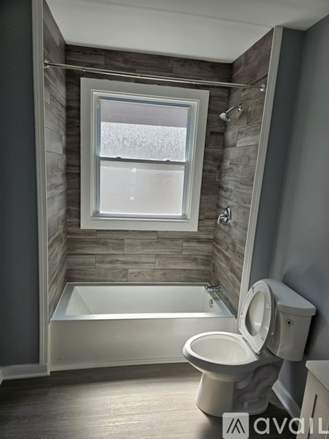 A bathroom with a toilet, tub, and window.