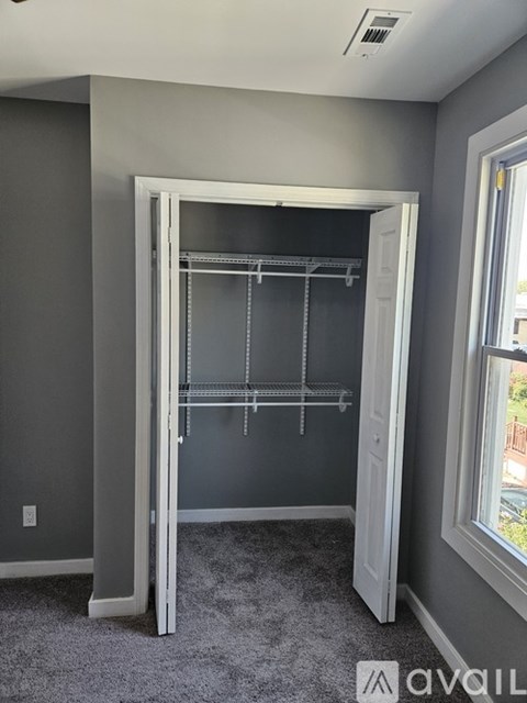 A room with a grey carpet and a grey wall with a white door.
