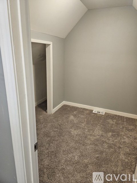 A room with carpeted floor and a doorway leading to another room.