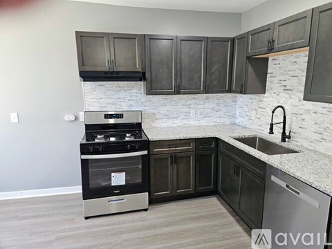 A kitchen with a stove, sink, and cabinets.