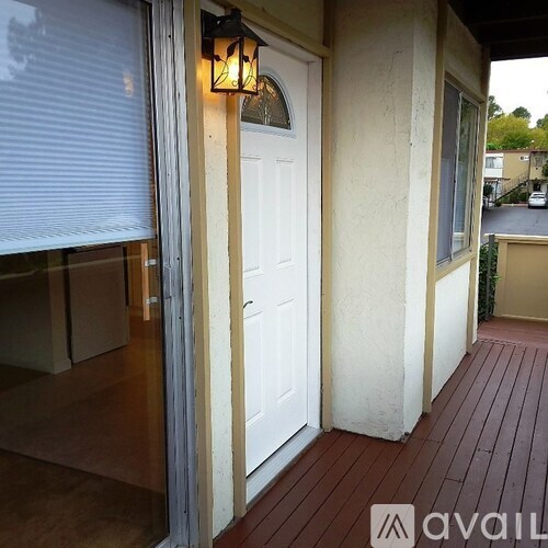 A white door is on the left side of a porch.