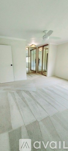 A room with a fan on the ceiling and a rug on the floor.