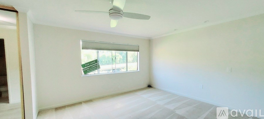 A room with a window and a fan on the ceiling.