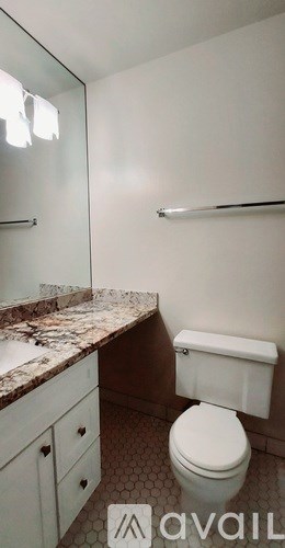 A white toilet in a bathroom with a marble counter top.