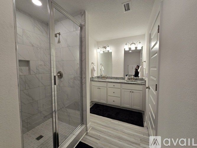 A bathroom with a marble tile shower and a vanity with a mirror above it.