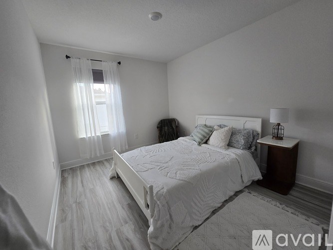 A bedroom with a large bed and a window with curtains.