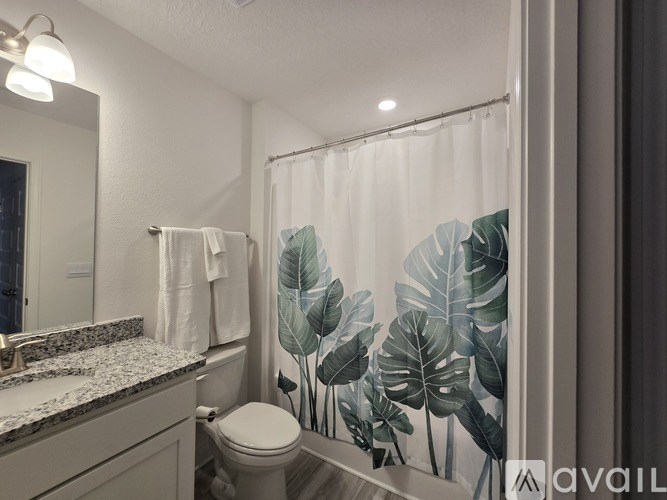 A bathroom with a leaf patterned shower curtain.