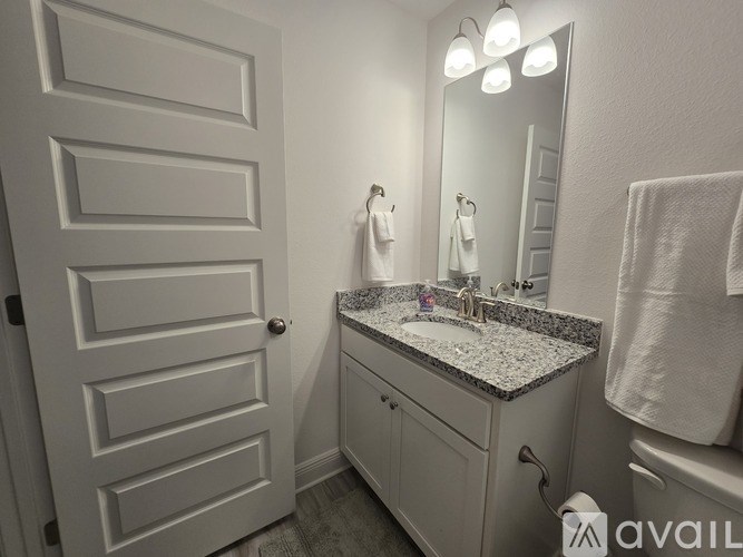 A bathroom with a sink, mirror, and towel rack.