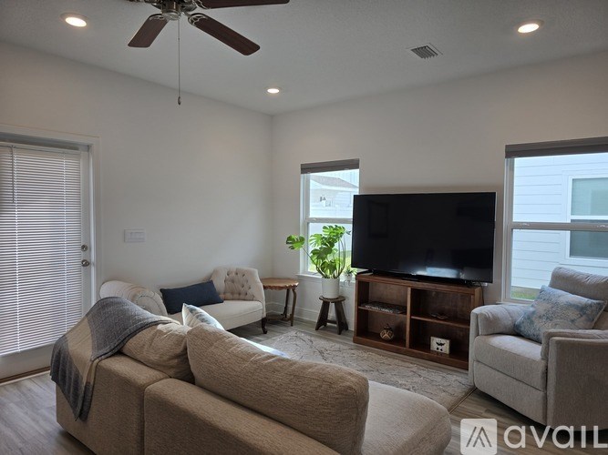 A living room with a couch, a chair, a television, and a plant.