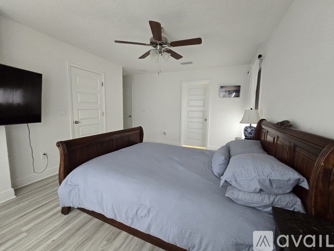 A bedroom with a large bed and a ceiling fan.