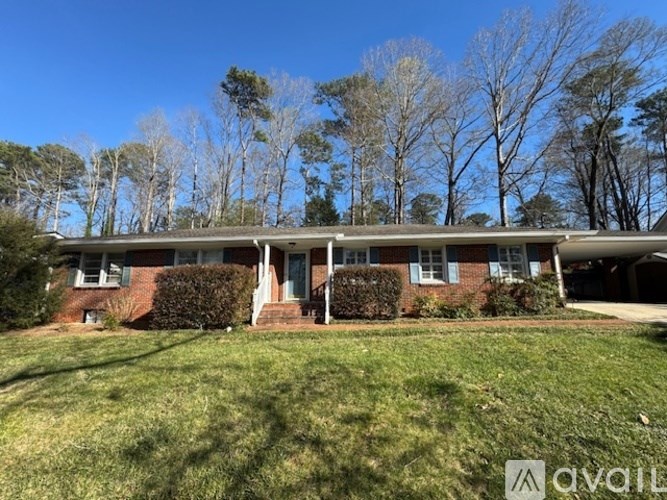 A house with a lawn in front and trees in the background.