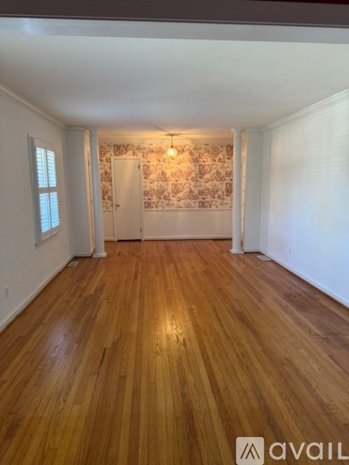 A room with wooden flooring and a patterned wallpapered wall.