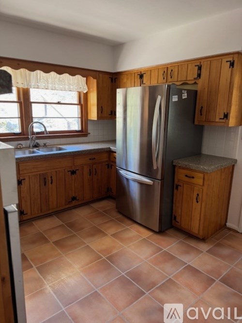 A kitchen with a refrigerator, sink, and wooden cabinets.