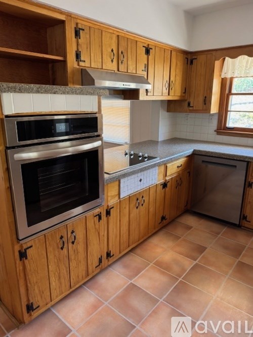 A kitchen with wooden cabinets and a tile floor.