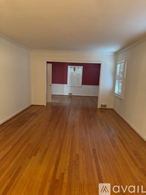 A room with wooden flooring and a red wall in the background.
