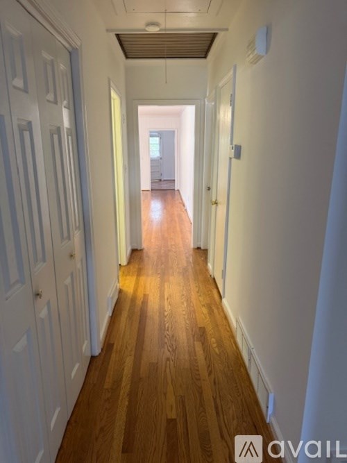 A long hallway with wooden floors and white walls.