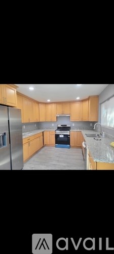 A kitchen with wooden cabinets and a stainless steel refrigerator.