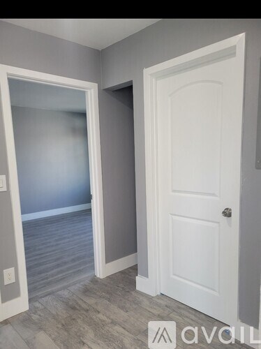 A white door is open to a room with grey walls.