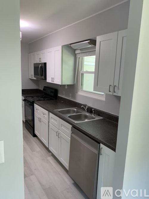 A kitchen with white cabinets and black countertops.