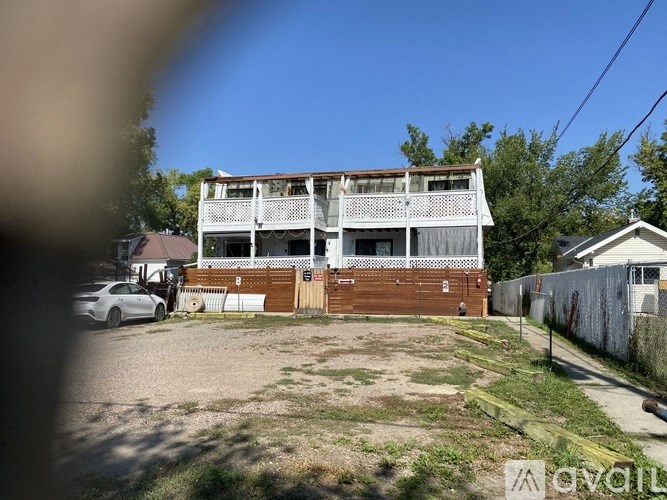 A two-story building with a white balcony and a car parked in front.