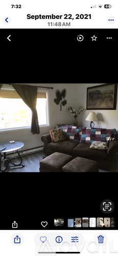 A living room with a brown couch and a window with curtains.