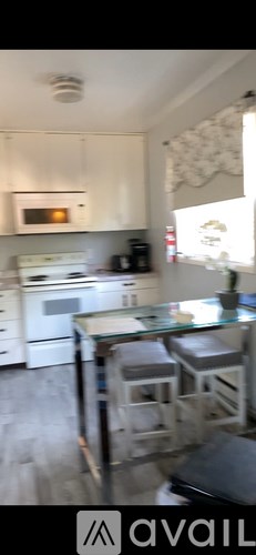A kitchen with white cabinets and a glass table.