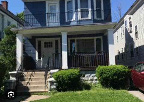 A blue house with a red car parked in front.