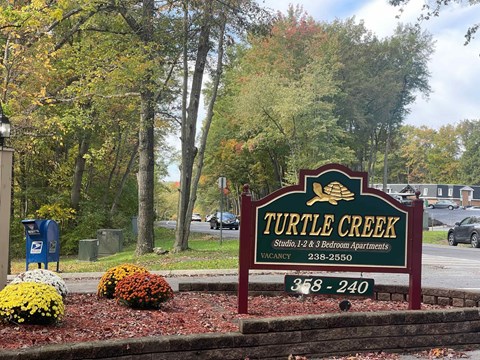A sign for Turtle Creek Studio, 1-2 & Bedroom Apartments with a phone number on it.