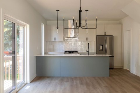 A modern kitchen with a large island and a chandelier.