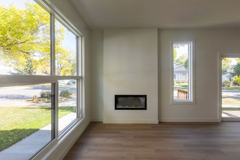 A modern living room with a fireplace and large windows.