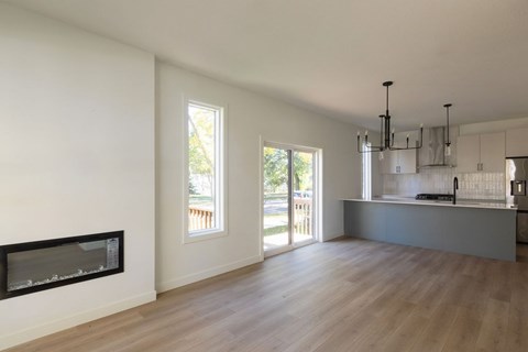 A modern kitchen with a fireplace and wooden floors.