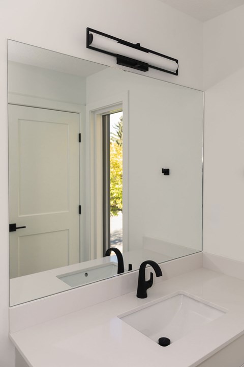 A white bathroom sink with a black faucet and a mirror above it.