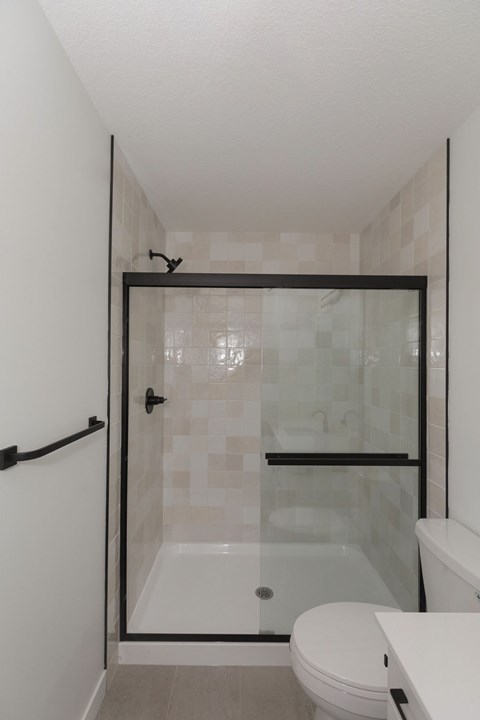 A white toilet sits next to a walk-in shower with a glass door.