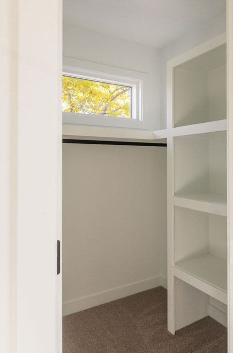 A white shelving unit in a room with a window.